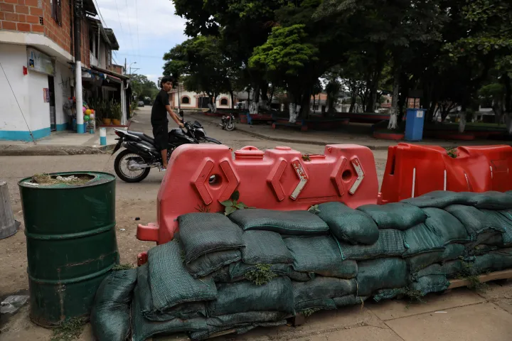 A man rides his motorcycle past a barricade blocking streets in Potrerito, Colombia