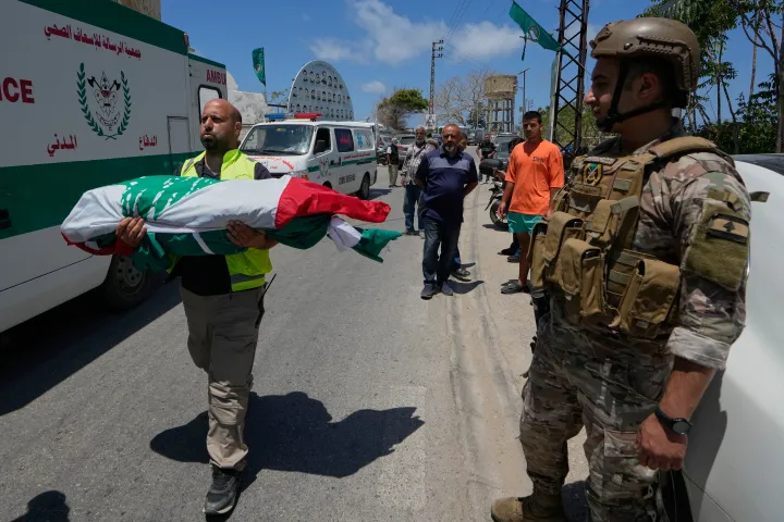 A paramedic volunteer carries a body, one of the six the family members who were killed 