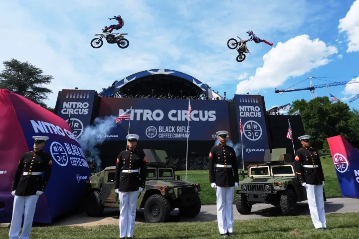 Motorsports athletes and stunt performers do a motorcycle jump ahead of the UFC 
