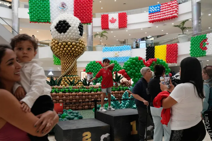 AP Shoppers stand in front of balloon flags of countries participating in the FIFA World Cup