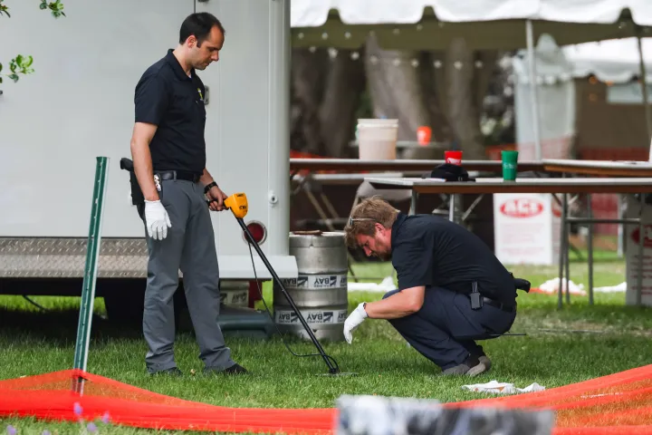AP nvestigators use a metal detector to look for shells after a shooting that left 12 people injured