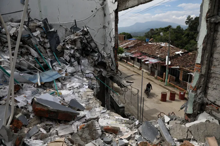 A man rides his motorcycle past the ruins of homes destroyed five months earlier in an attack