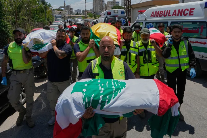 Mourners and paramedics carry the bodies of family members killed