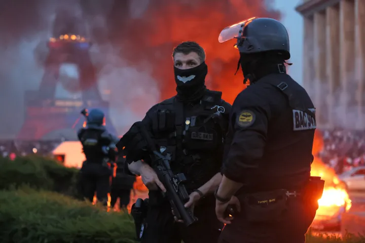 A car burns and fireworks explode as police watch PSG supporters celebrate in Paris