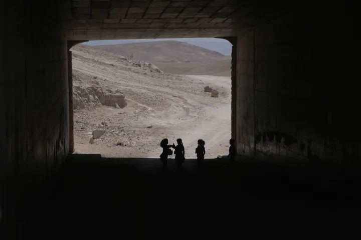Palestinian children go through a vehicles tunnel on their way home