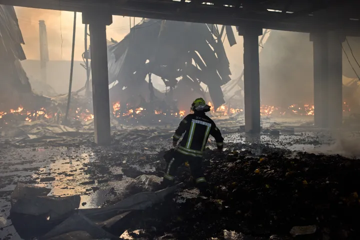 A firefighter tries to extinguish a fire in a destroyed warehouse after Russian drone attacks on the outskirts of Kyiv