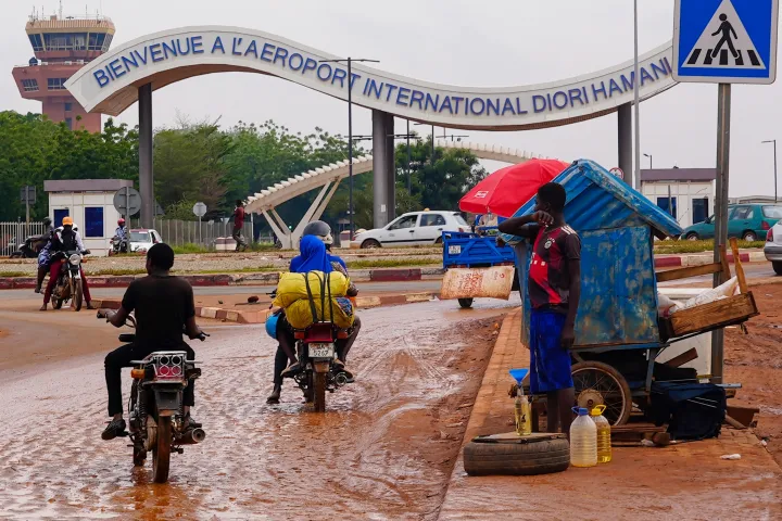 Motorcyclists ride by the entrance of the airport in Niamey, Niger,