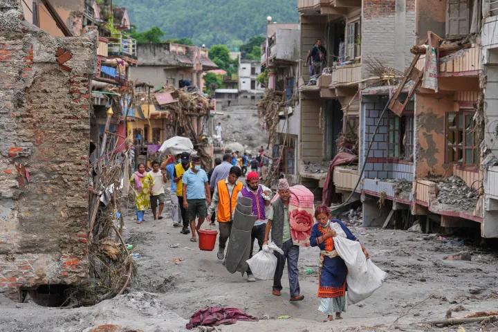 AP Residents carry their belongings salvaged from their damaged homes filled with mud and debris in Devighat, in Nepal's Nuwakot district