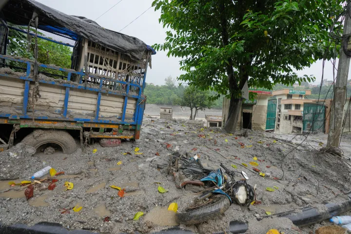 Damaged buildings and vehicles lie in mud and slush caused by flash flooding in Nepal's Nuwakot district