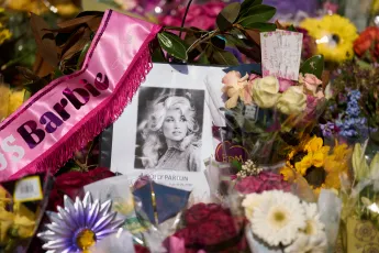 A portrait of the late Dolly Parton surrounded by flowers and cards in a memorial sits outside her home