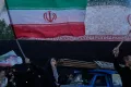 A woman waves an Iranian flags as she chants slogans against Iran and U.S. talks