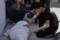 Omar Klaub, injured in an Israeli strike, mourns beside the body of his mother