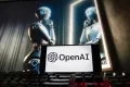 Το λογότυπο της OpenAI εμφανίζεται σε κινητό τηλέφωνο, με μια εικόνα σε οθόνη υπολογιστή που δημιουργήθηκε από το μοντέλο μετατροπής κειμένου σε εικόνα Dall-E του ChatGPT.